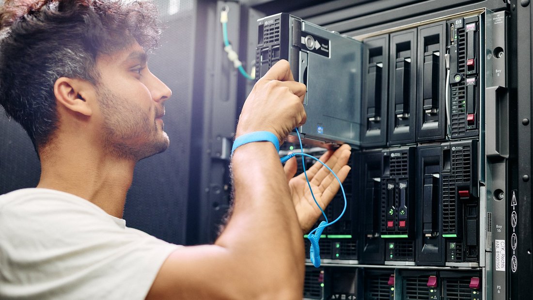 in Techniker arbeitet an einem Serverrack und schließt ein Netzwerkkabel an einen Server an.