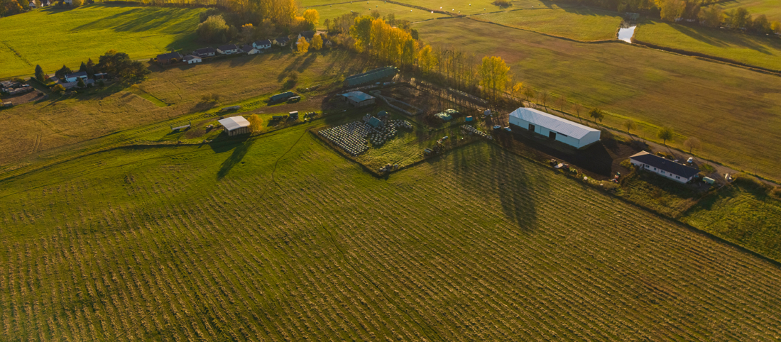 Eine Luftaufnahme eines landwirtschaftlichen Betriebes mit Stallungen und Feldern