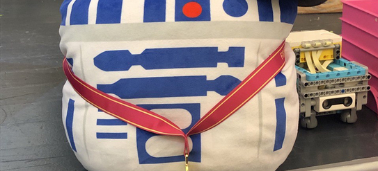 Ein Kuscheltier von C3PO aus Star Wars mit einer Medaille