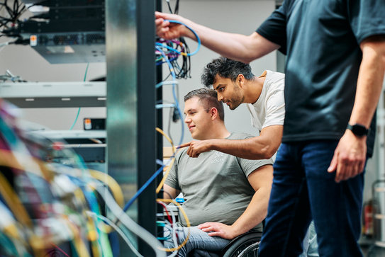 Mitarbeitende arbeiten an einem Serverturm