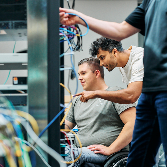 Mitarbeitende schauen gemeinsam in einen Serverturm