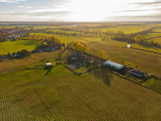 Eine Luftaufnahme eines landwirtschaftlichen Betriebes mit Feldern und Stallungen