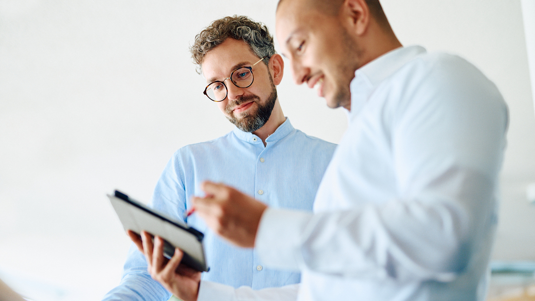 Zwei Männer schauen gemeinsam auf ein Tablet