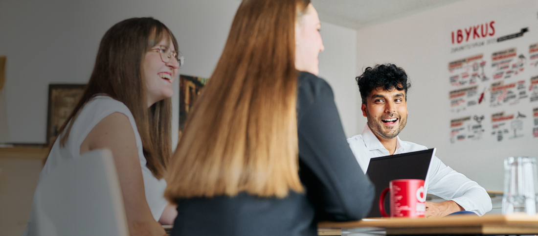 Drei Mitarbeitende der IBYKUS AG sitzen gemeinsam an einem Tisch.