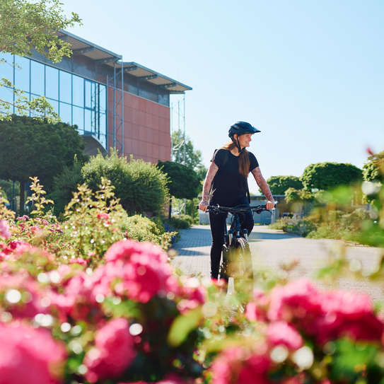 Eine Frau fährt mit ihrem Fahrrad über das IBYKUS Firmengelände