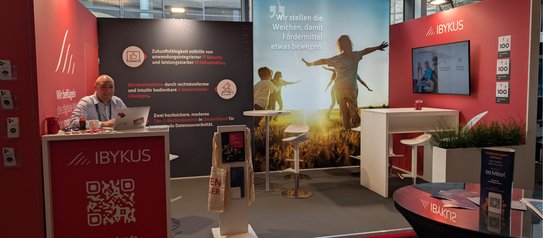 Ein Mitarbeitender am Stand der IBYKUS AG auf dem Kongress "Digitaler Staat"
