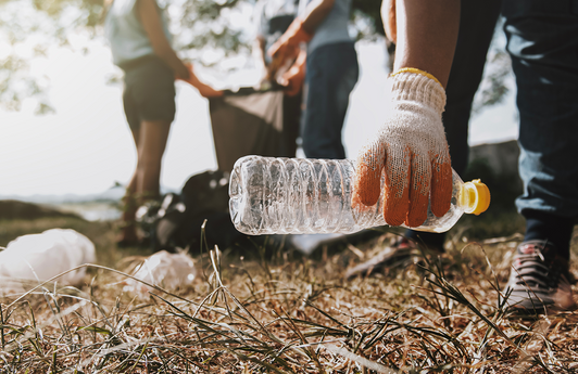 Eine Person greift auf dem Boden nach einer Plastikflasche