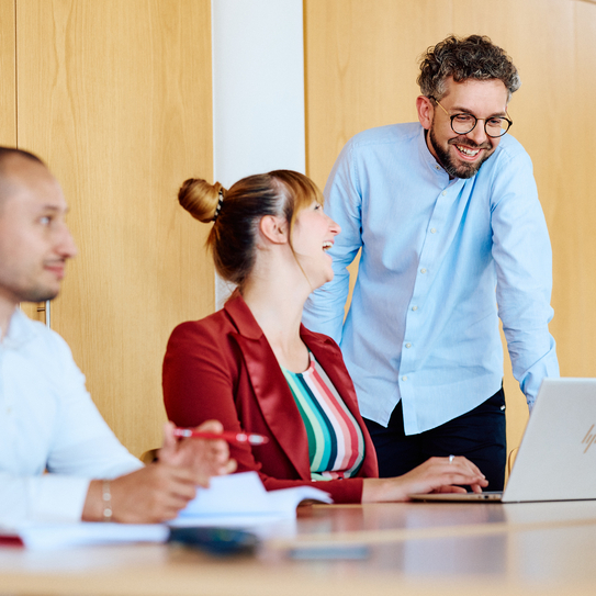 Kolleg:innen im Meeting mit Laptop und Unterlagen